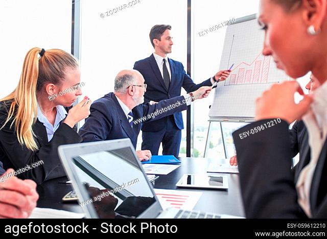 Executive giving a presentation at flipchart in front of his co-workers in office