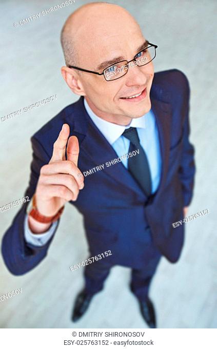 Successful employee in eyeglasses and suit looking at camera with smile