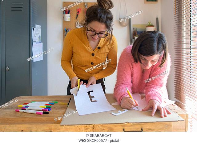 Two women making stencils for printing sweatshirts