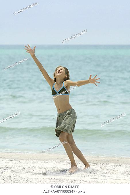 Girl running with arms up on beach