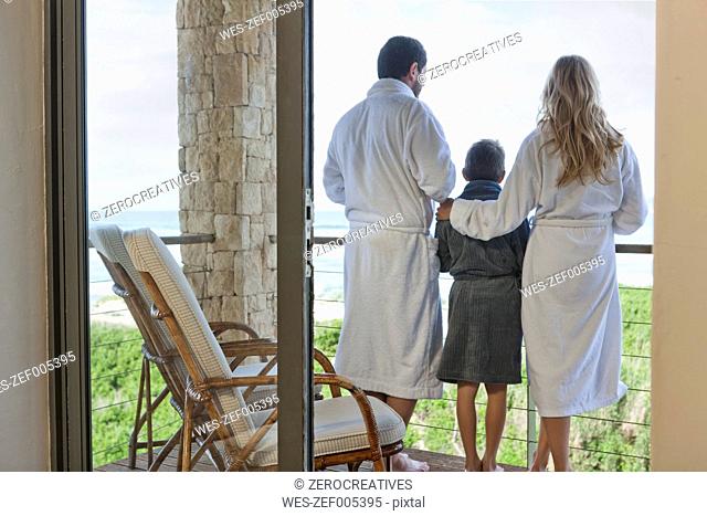 Family in bathrobes standing on patio of beach house