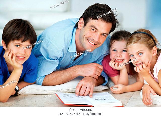 Portrait of handsome man helping children with their homework at home