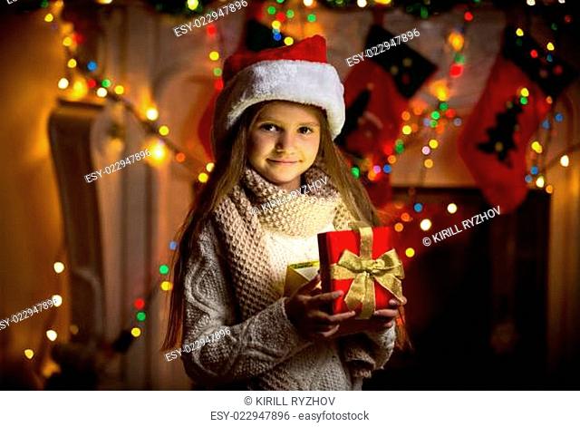 portrait of smiling girl opening sparkling gift box at Christmas