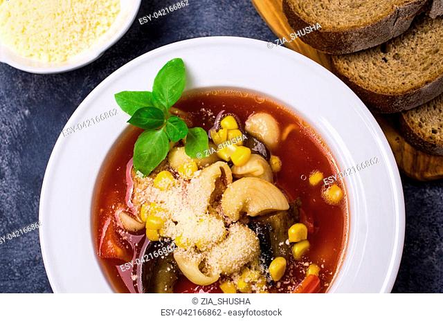Traditional Italian soup with pasta and vegetables in bowl on stone background. Selective focus