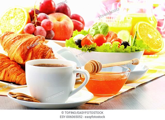Breakfast with coffee, orange juice, croissant, egg, vegetables and fruits