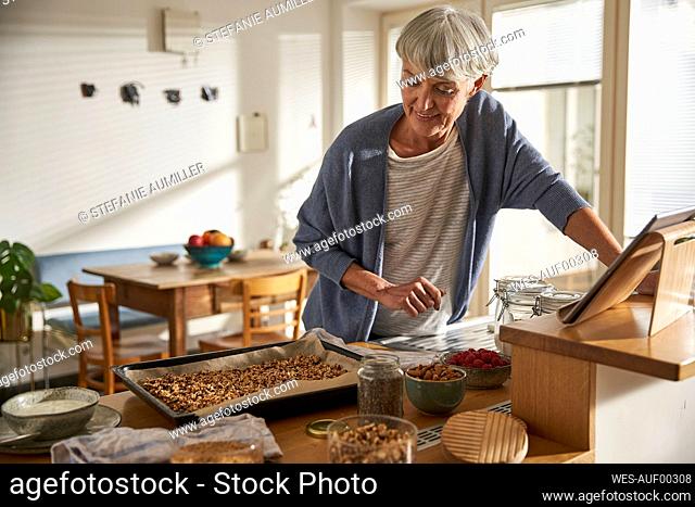 Senior woman preparing granola in kitchen