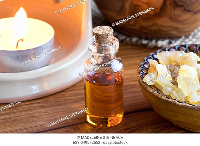 A dark bottle of frankincense essential oil with frankincense resin and an aroma lamp