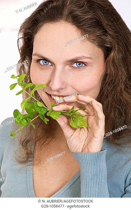 young woman breathing a sprig of fresh mint