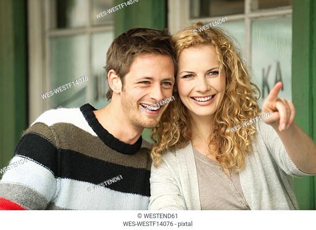 Germany, Bavaria, Munich, Young couple at Viktualienmarkt, woman pointing, smiling, portrait