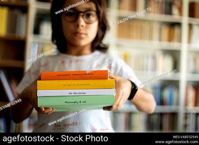 Boy holding stack of four books
