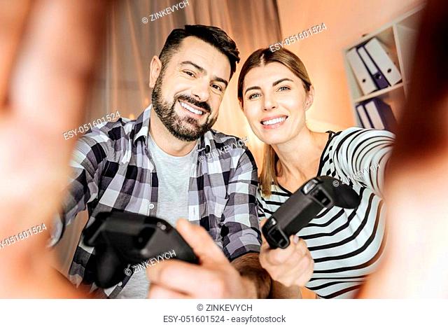 Keep smiling. Cheerful couple expressing positivity and touching camera while looking forward