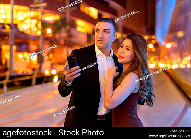 Portrait of couple outdoors at night in the city
