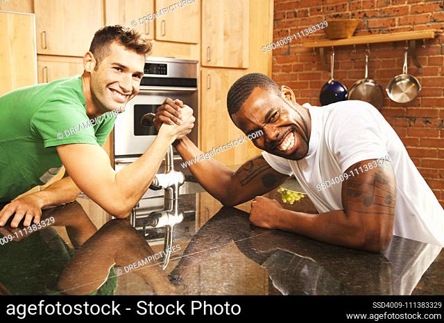 Men arm wrestling in kitchen