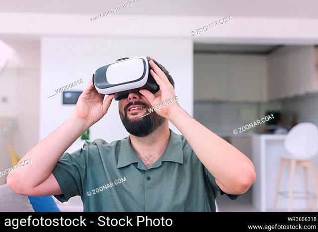 handsome hipster man with beard trying vr glasses at modern home