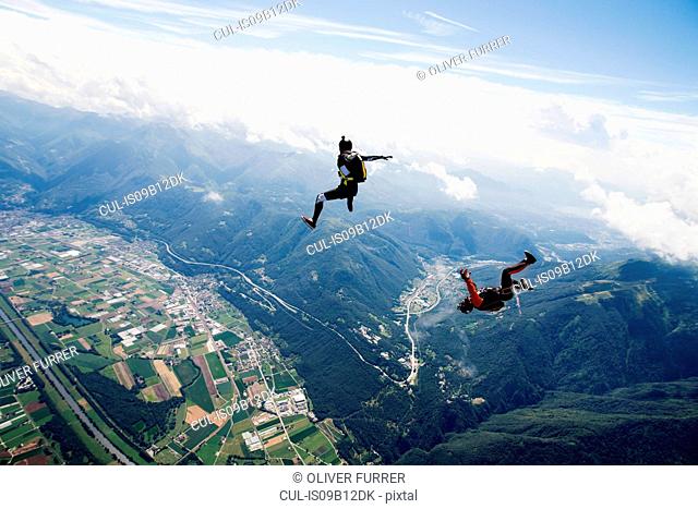 Freestyle skydiving team training together. One man performing air-ballet, another jumper is filming with video camera on helmet, Locarno, Tessin, Switzerland