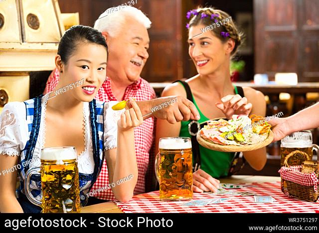In Pub - friends in Tracht, Dirndl and Lederhosen drinking a fresh beer in Bavaria, Germany