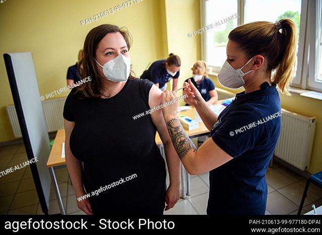 13 June 2021, Mecklenburg-Western Pomerania, Wismar: A woman is vaccinated against the coronavirus with the Johnson & Johnson vaccine by a doctor's assistant in...