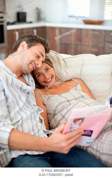 Pregnant woman reading magazine with husband