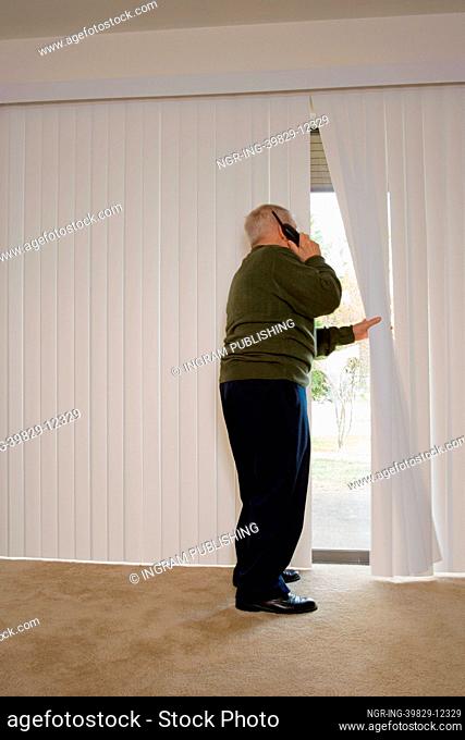 Elderly man on phone and looking out of window