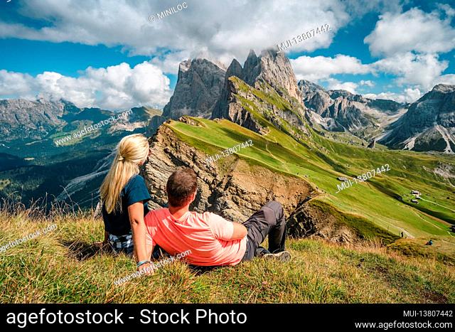 A couple enjoy landscape of Seceda peak in Dolomites Alps, Odle mountain range, South Tyrol, Italy, Europe. Travel vacation concept