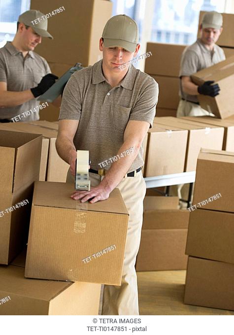 USA, New Jersey, Jersey City, men packing boxes in warehouse