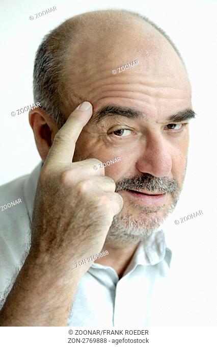 Mann zeigt mit dem Zeigefinger an die Stirn