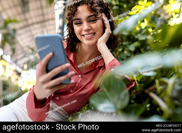 Happy woman using smart phone in garden