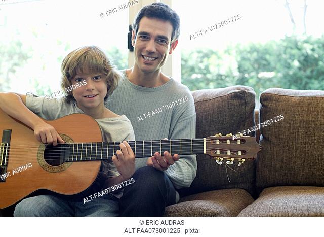 Father teaching son how to play guitar