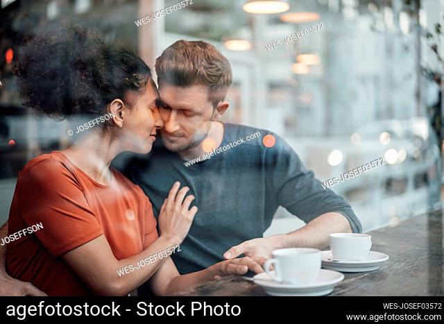 Couple sitting face to face with eyes closed at cafe