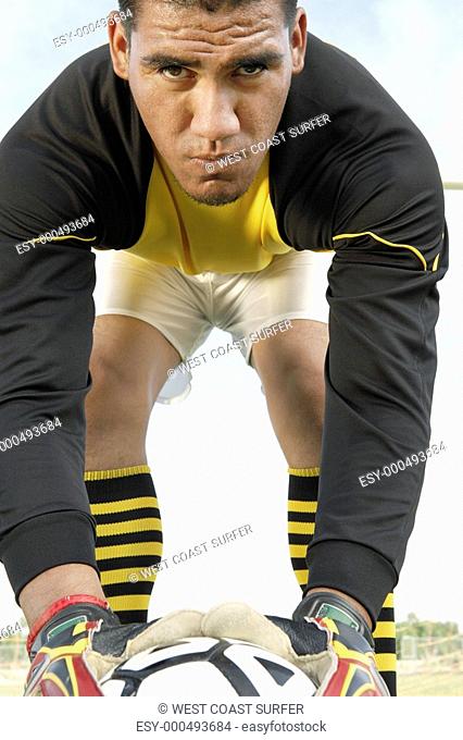 Goalkeeper bending down with ball portrait