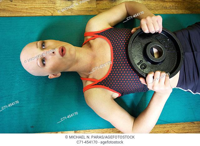 Caucasian Woman with alopecia areata/cancer survivor working out at the gym