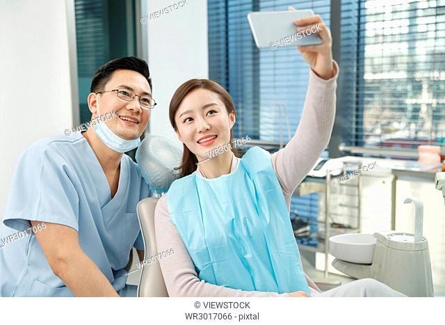 Male dentists and female patients use mobile phones to take pictures