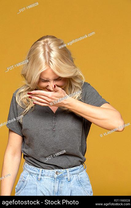 Happy woman laughing on yellow background
