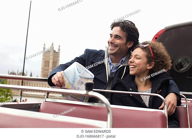 Couple riding double decker bus past Parliament Building in London