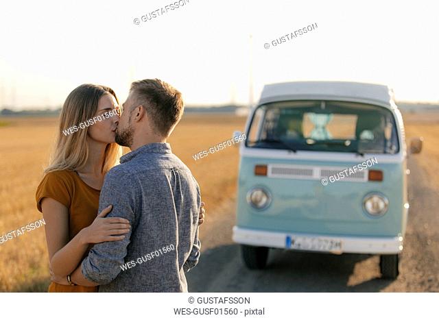 Young couple kissing at camper van in rural landscape
