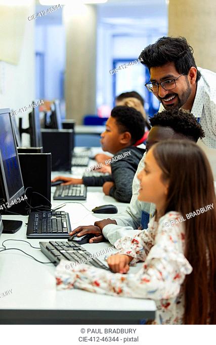 Teacher helping junior high students using computer in computer lab
