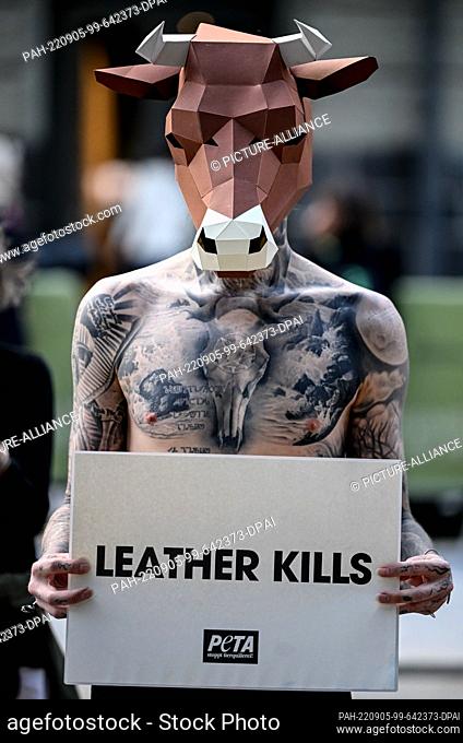 05 September 2022, Berlin: A protester of the animal rights organization PETA holds signs with the inscription ""Leather kills"" in the air at the Mercedes-Benz...