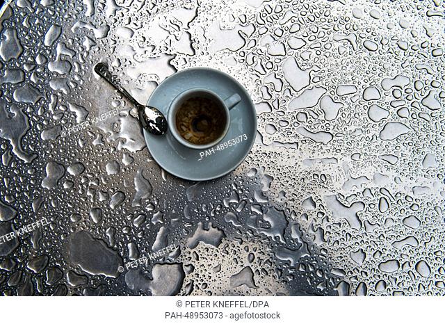 An empty espresso cup has been placed on a wet table of a sidewalk café in Munich, Germany, 27 May 2014. Photo: PETER KNEFFEL/dpa | usage worldwide
