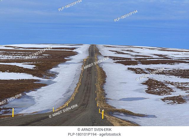 Road leading through the tundra towards the mountain range Lambafjöll / Lambafjoell in winter, Northeastern Region / Norðurland eystra, Iceland