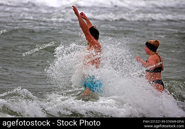21 December 2023, Mecklenburg-Western Pomerania, Warnemünde: Hardened winter bathers take a dip in the storm-lashed water on the Baltic Sea beach