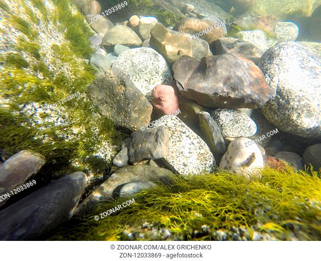 underwater river rocks being washed by mountain stream