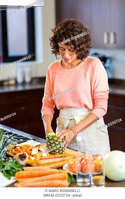 Hispanic woman slicing pineapple
