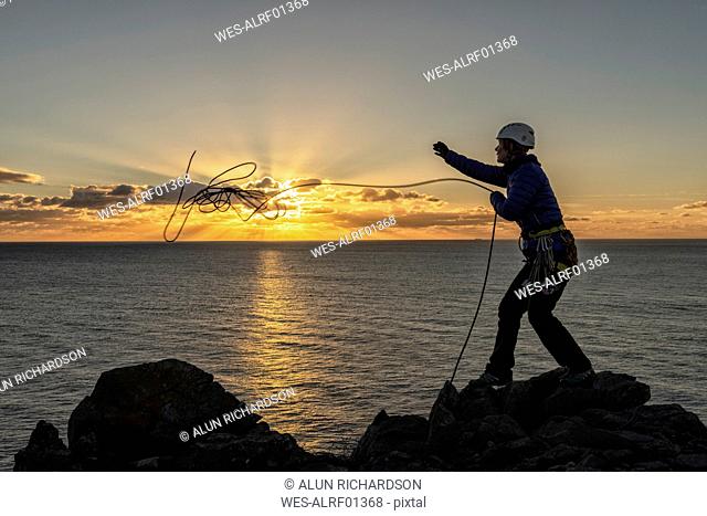 United Kingdom, Wales, Pembrokeshire, St Govan's, female climber throwing rope