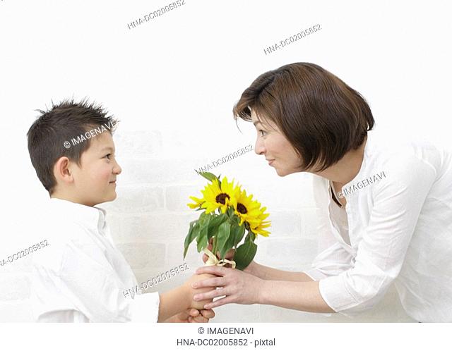 Son giving bouquet to mother
