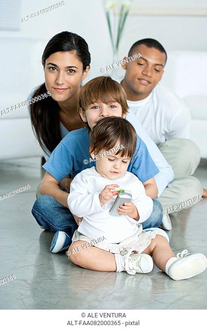 Mother and children sitting on floor at home