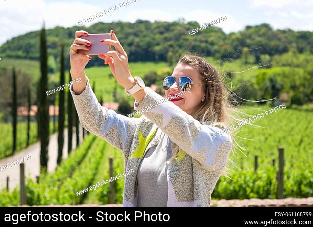 Young woman taking selfie, photographing herself in tourist spot, grape plantation, winery