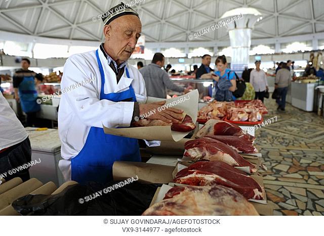 Tashkent, Uzbekistan - May 01, 2017: Unknown old Uzbek man packing horse meat at Chorsu market