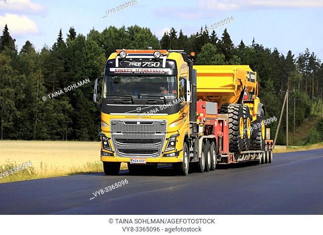Jokioinen, Finland. July 26, 2019. Yellow Volvo FH16 of Kosken Autokeskus Oy hauls Volvo A45G Full Suspension articulated hauler along highway