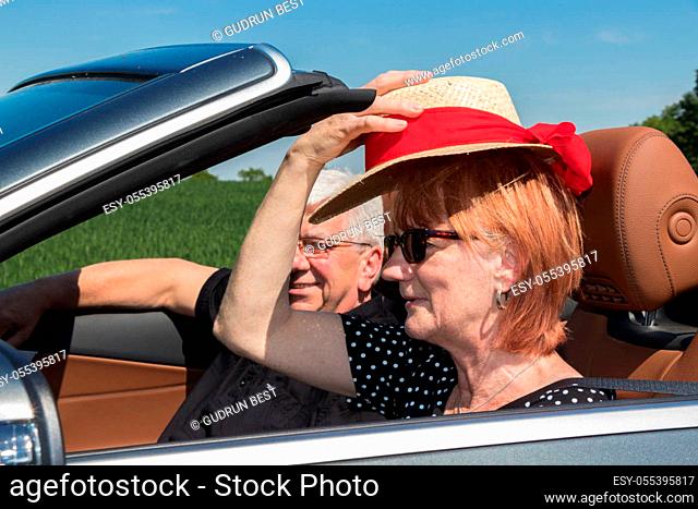 Beautiful older woman with partner in a luxury convertible car