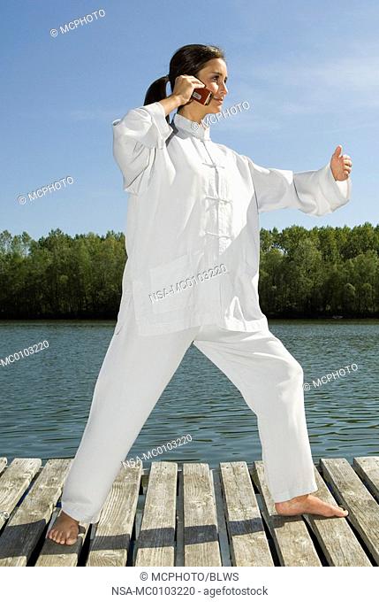 Young woman practising Tai Chi and phoning